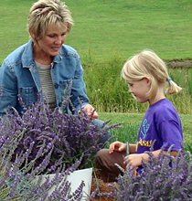 Norma DeCamp Burns examines lavender with a girl visiting the farm.