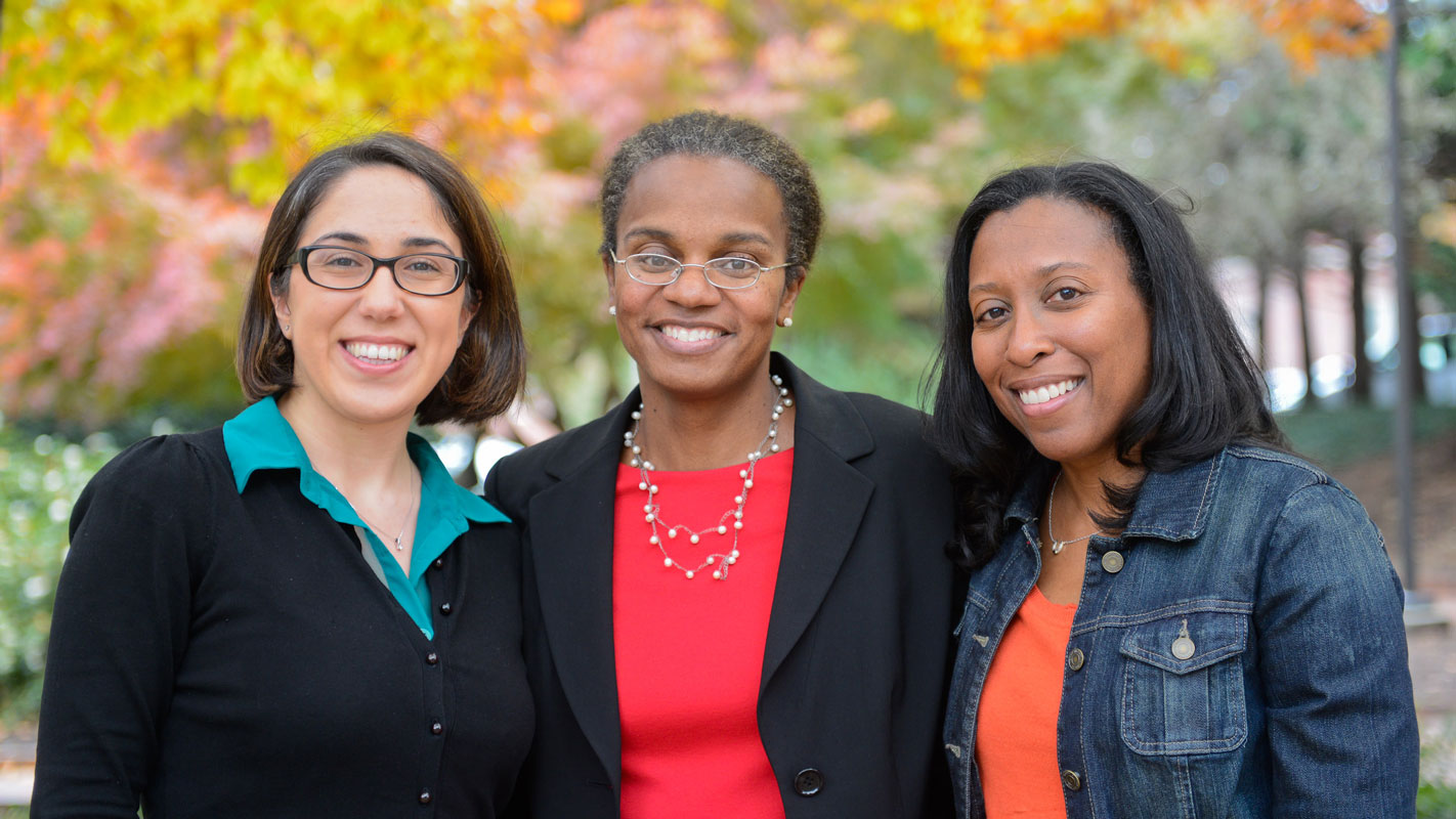 Three NC State industrial and systems engineers stand side by side in a garden on campus.