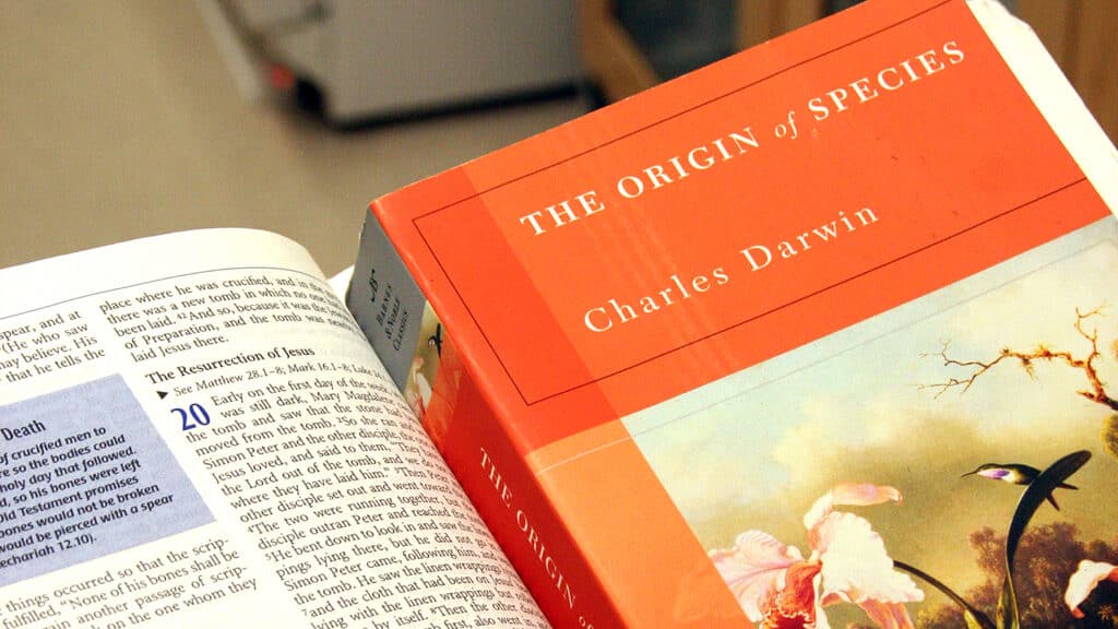 Close up of Darwin's Origin of Species resting on the open pages of a Bible.
