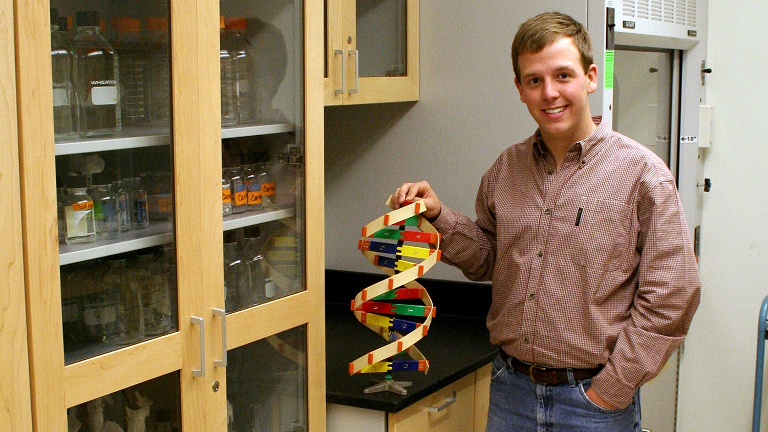 John Coggin holding a model of a DNA double helix.