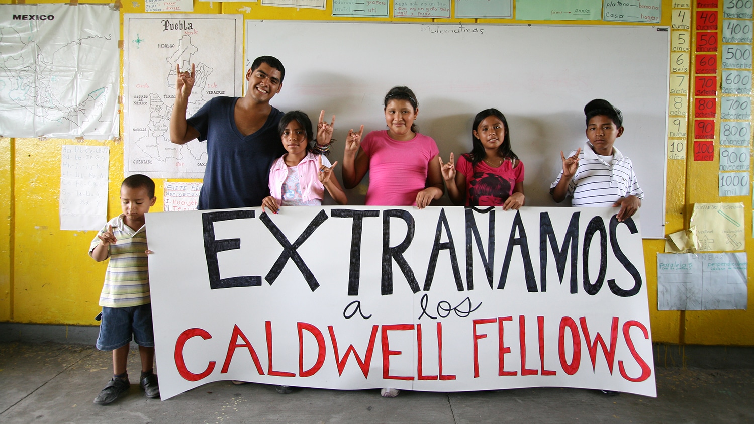 Saul Flores and children hold a banner thanking the Caldwell Fellows for their support.