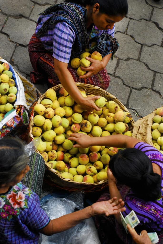 Women sorting fruit at an outdoor market.