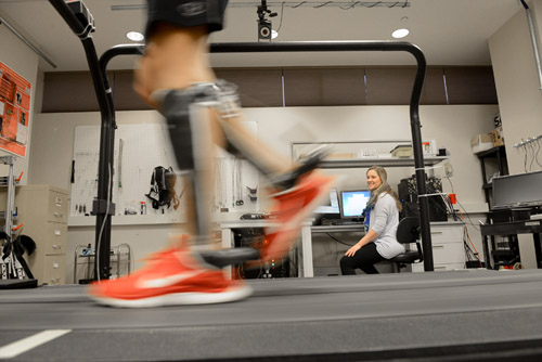 Graduate student Audrey Westbrook looks on as Dr. Bruce Wiggin uses exoskeleton devices to walk on a treadmill. The devices increase walking efficiency by 7 percent in able-bodied adults. Photo courtesy of Marc Hall, NC State University.