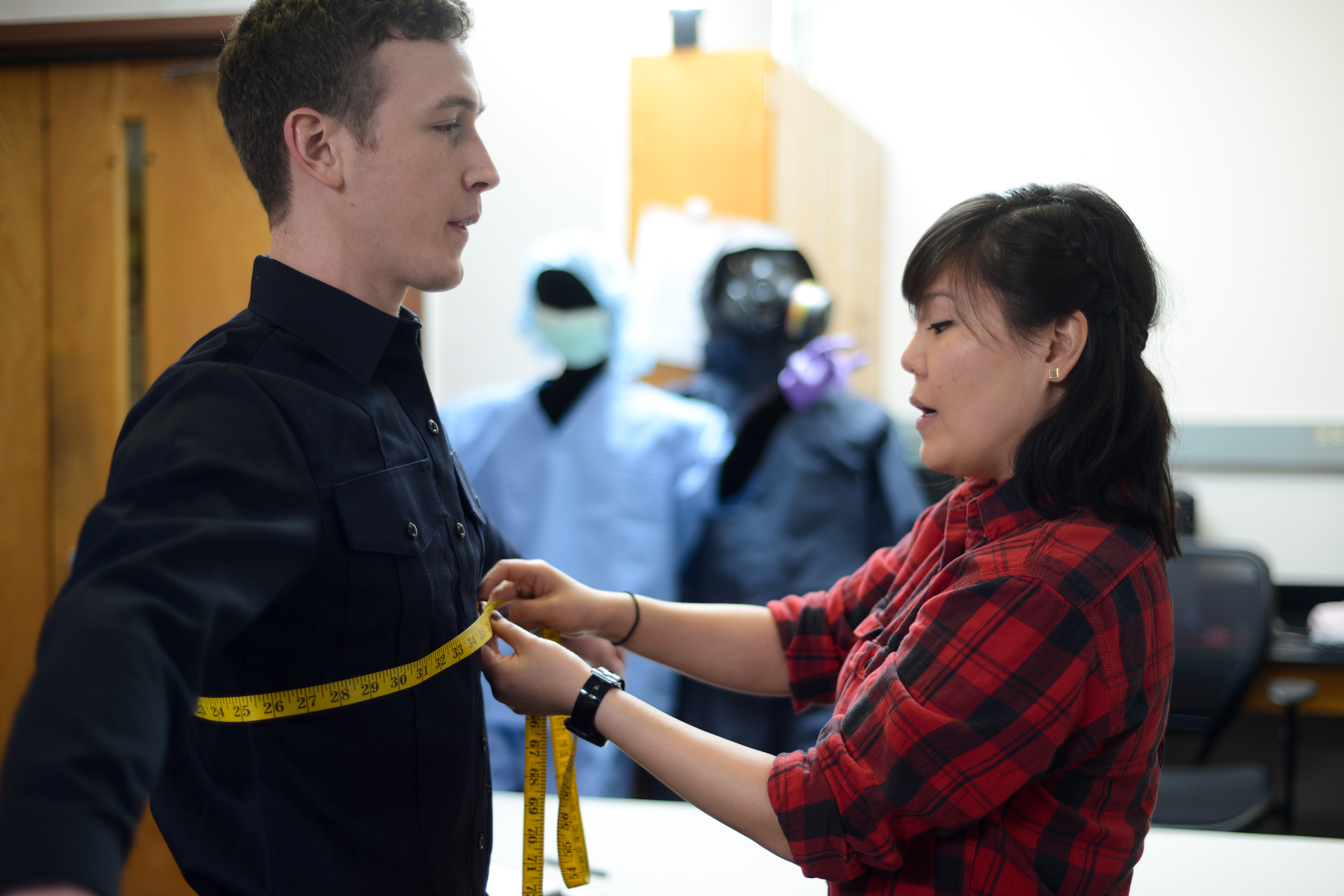 Researcher measures uniform shirt's fit on doctoral student