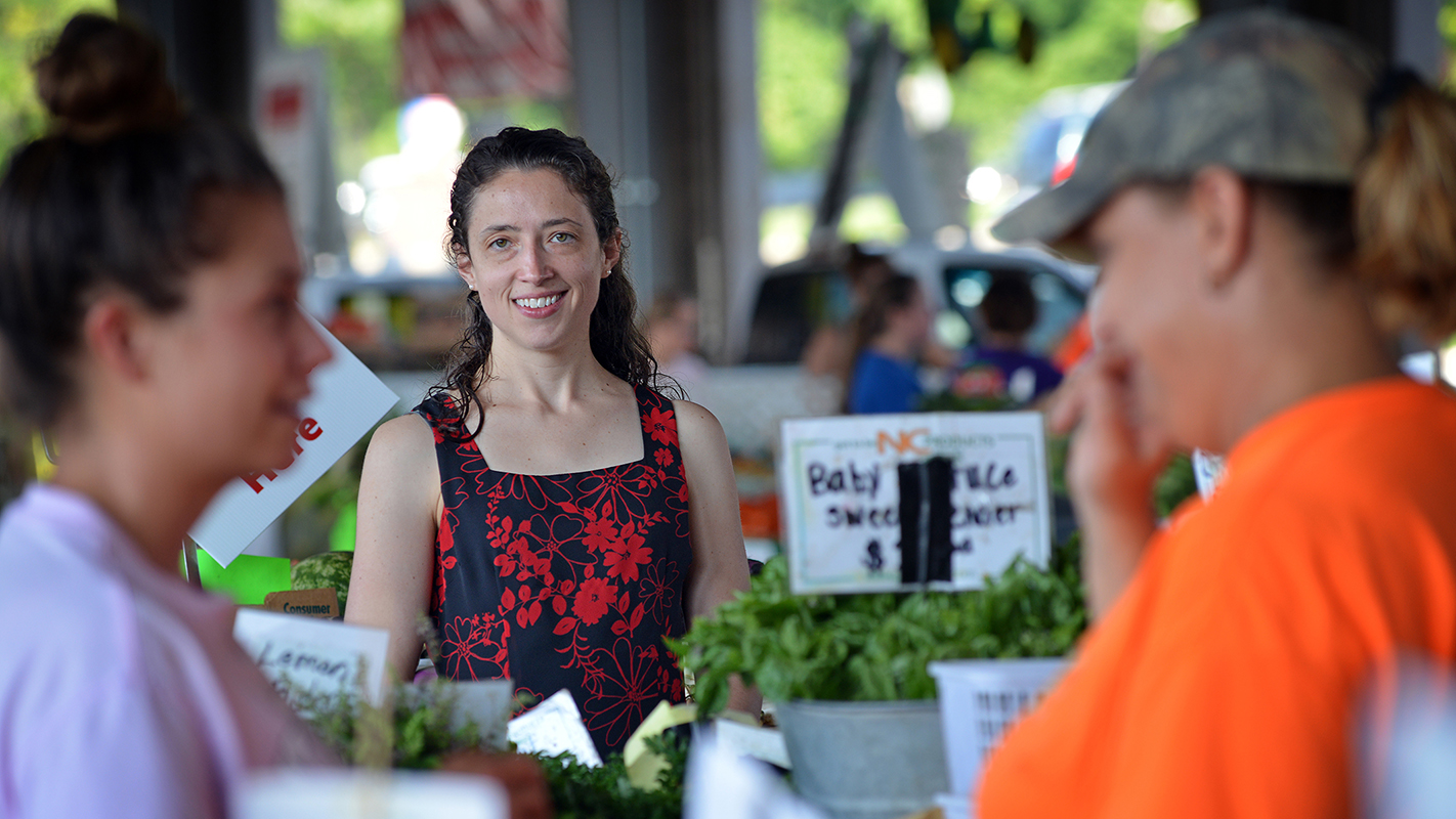 A woman listens in on a conversation between two merchants at the North Carolina famers market.