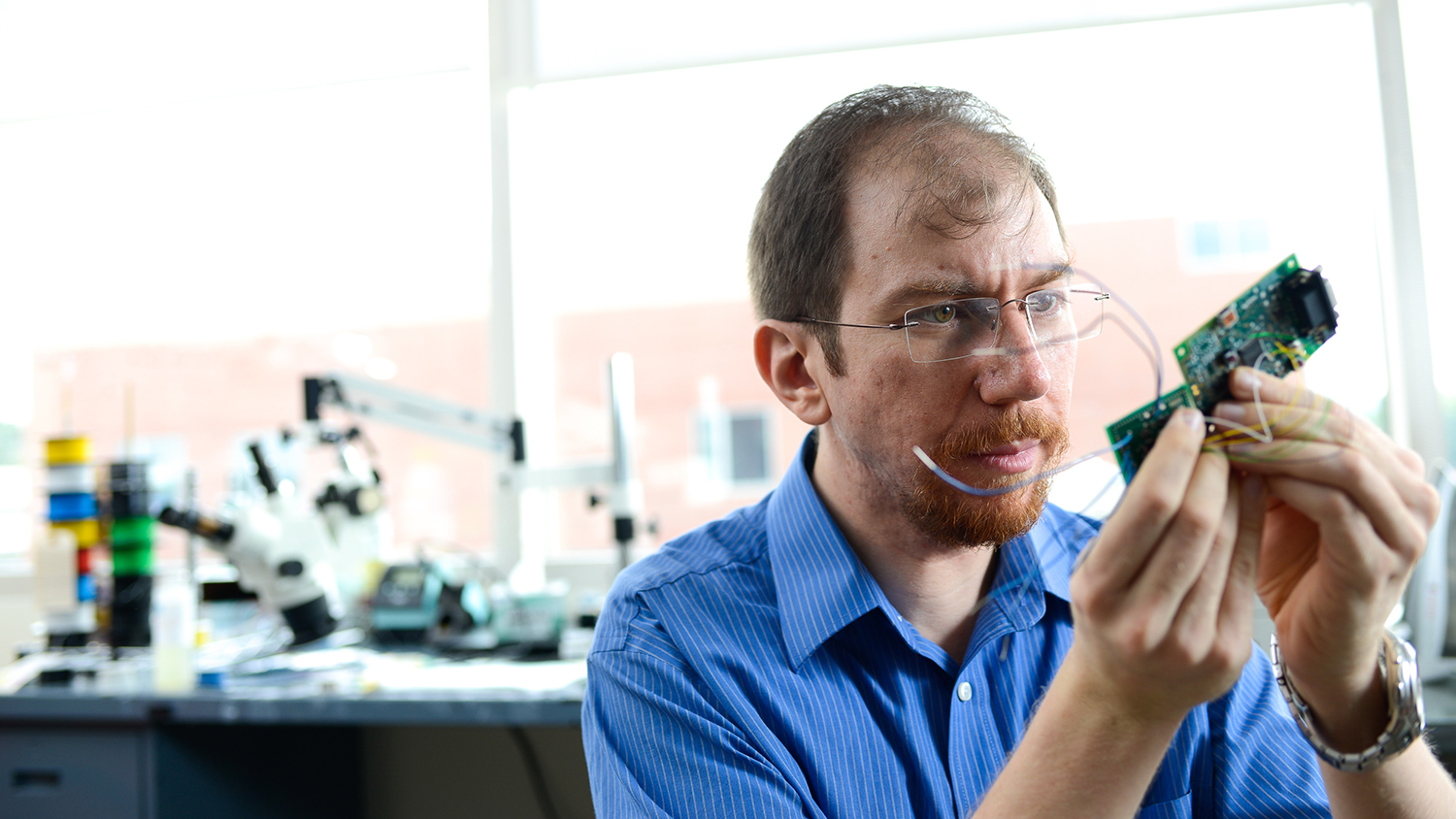 Alper Bozkurt holding up a device in his lab on NC State's Centennial Campus.