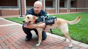 Dave Roberts holding a dog wearing his communications harness.