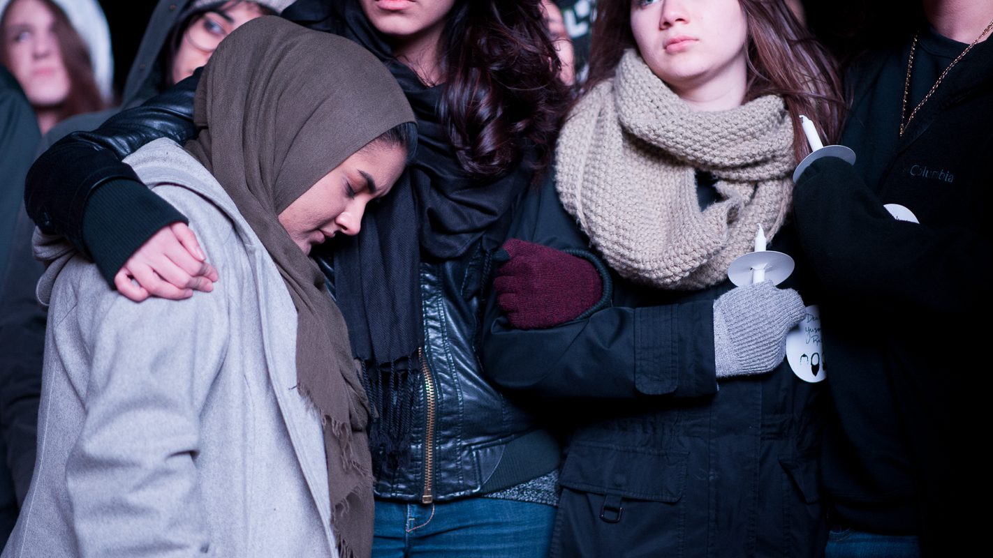 A participant takes comfort in a friend’s embrace during the program.