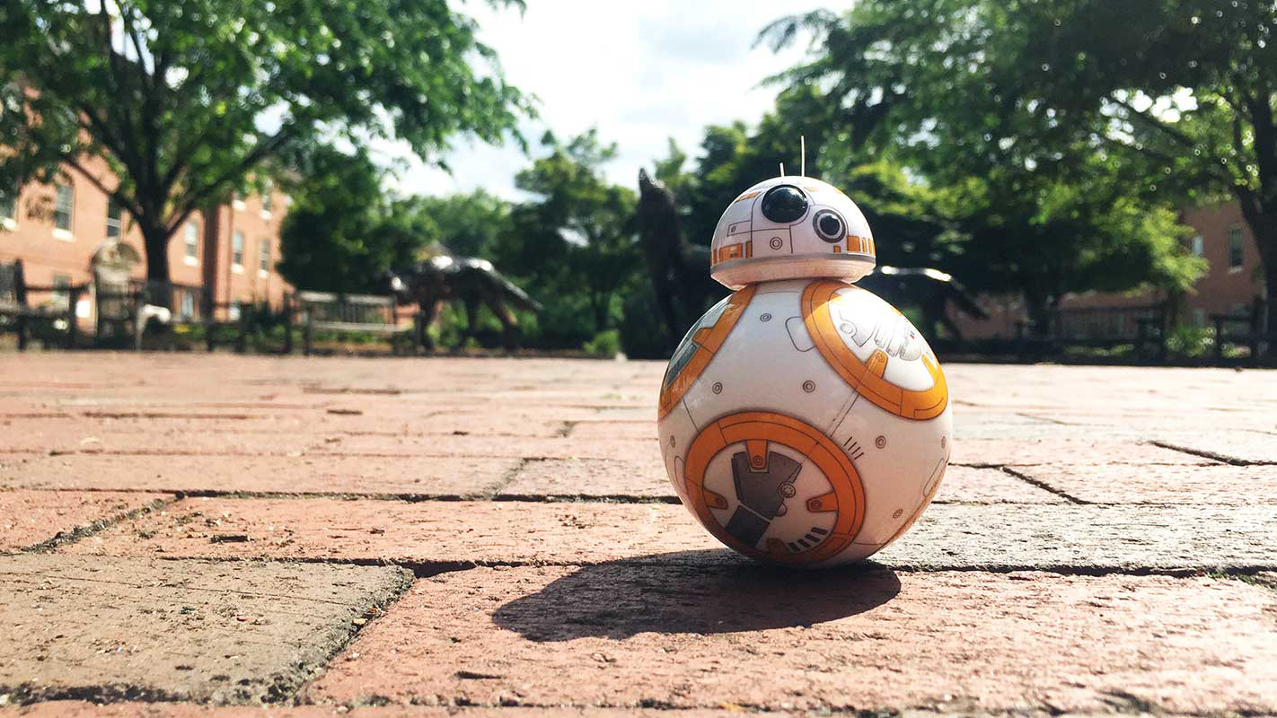 A brave toy droid rolls alone in front of the wolves at NC State's Wolf Plaza.
