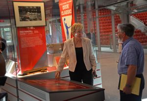 Athletics Director Debbie Yow (c) demonstrates during a media tour how the original "noise meter" lights up on display in the Grand Hallway.