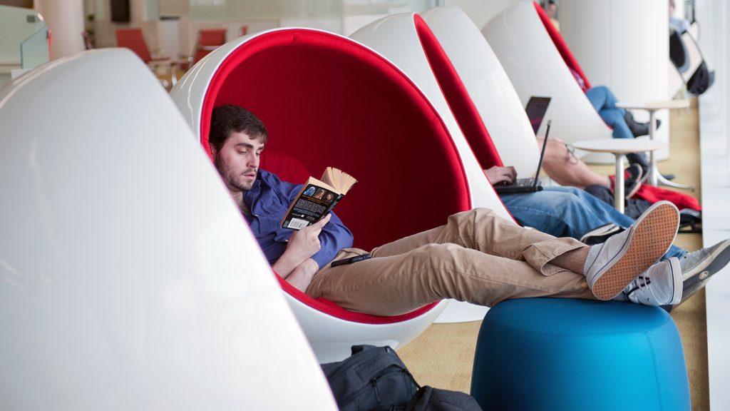 An NC State student lounges in a Ball Chair at the Hunt Library.