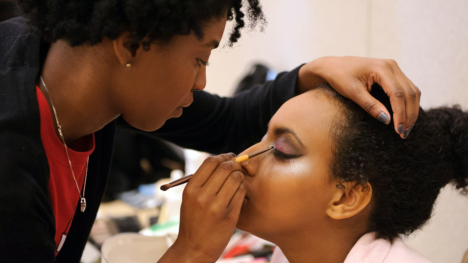 A makeup artist applies her craft to a student model.