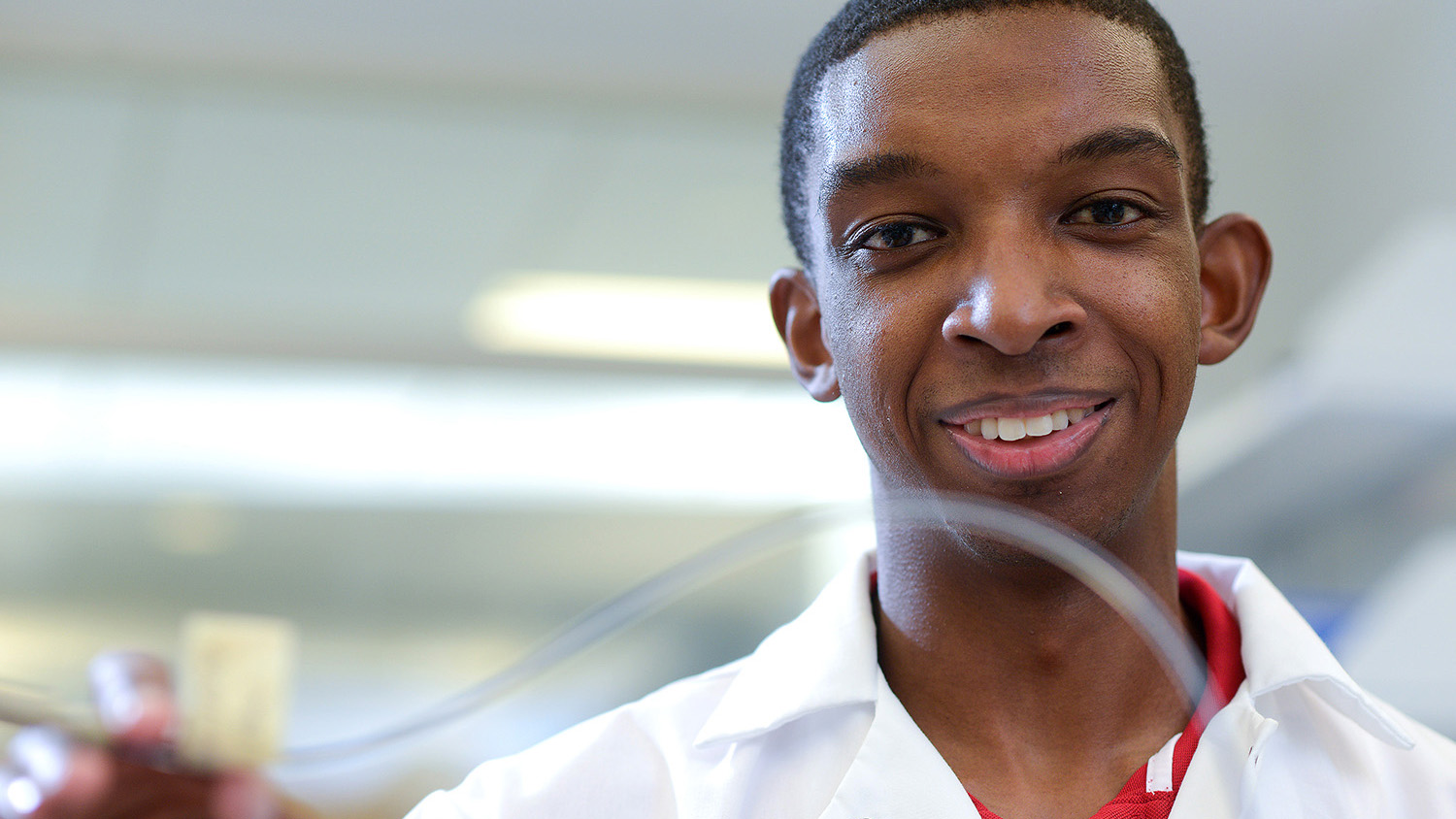 Kobi Felton holding a plastic tube in the lab.