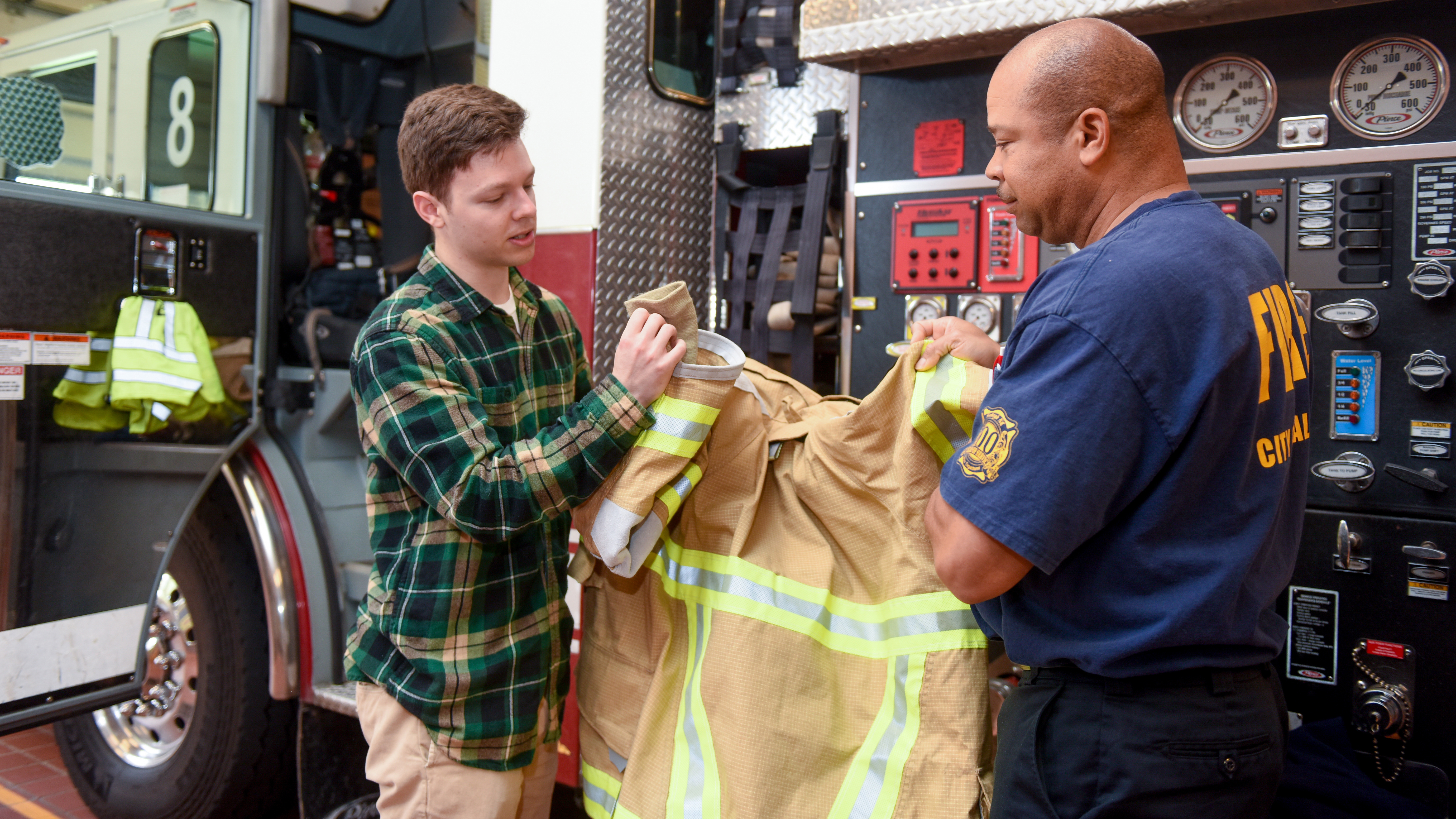 NC State Textiles student looks at gear with Raleigh firefighter