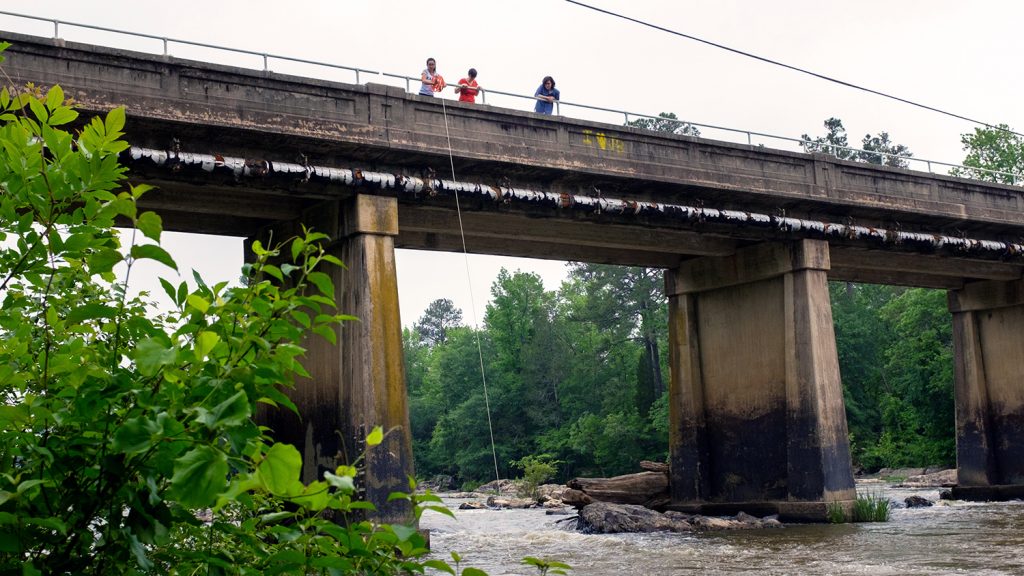 The Knappe group take water samples from a bridge over the Haw River.