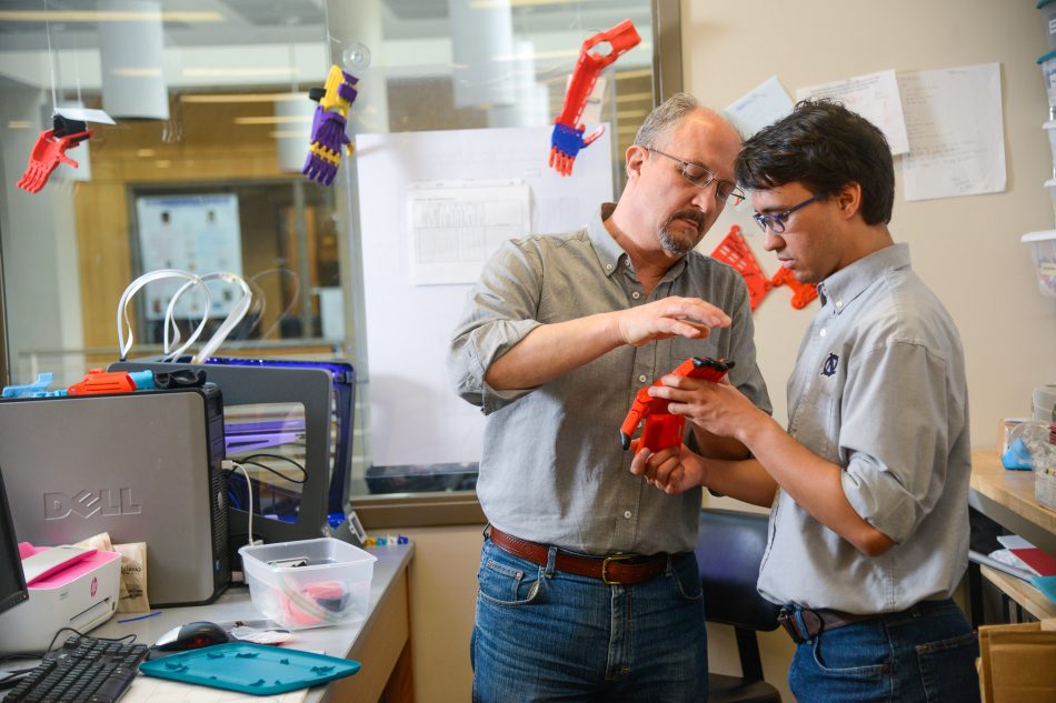 Timothy and David Calhoun look at a prosthetic hand in the Helping Hand Project lab.