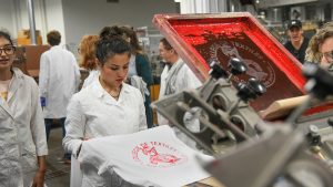 A student looks over her work on a screen-printed t-shirt.