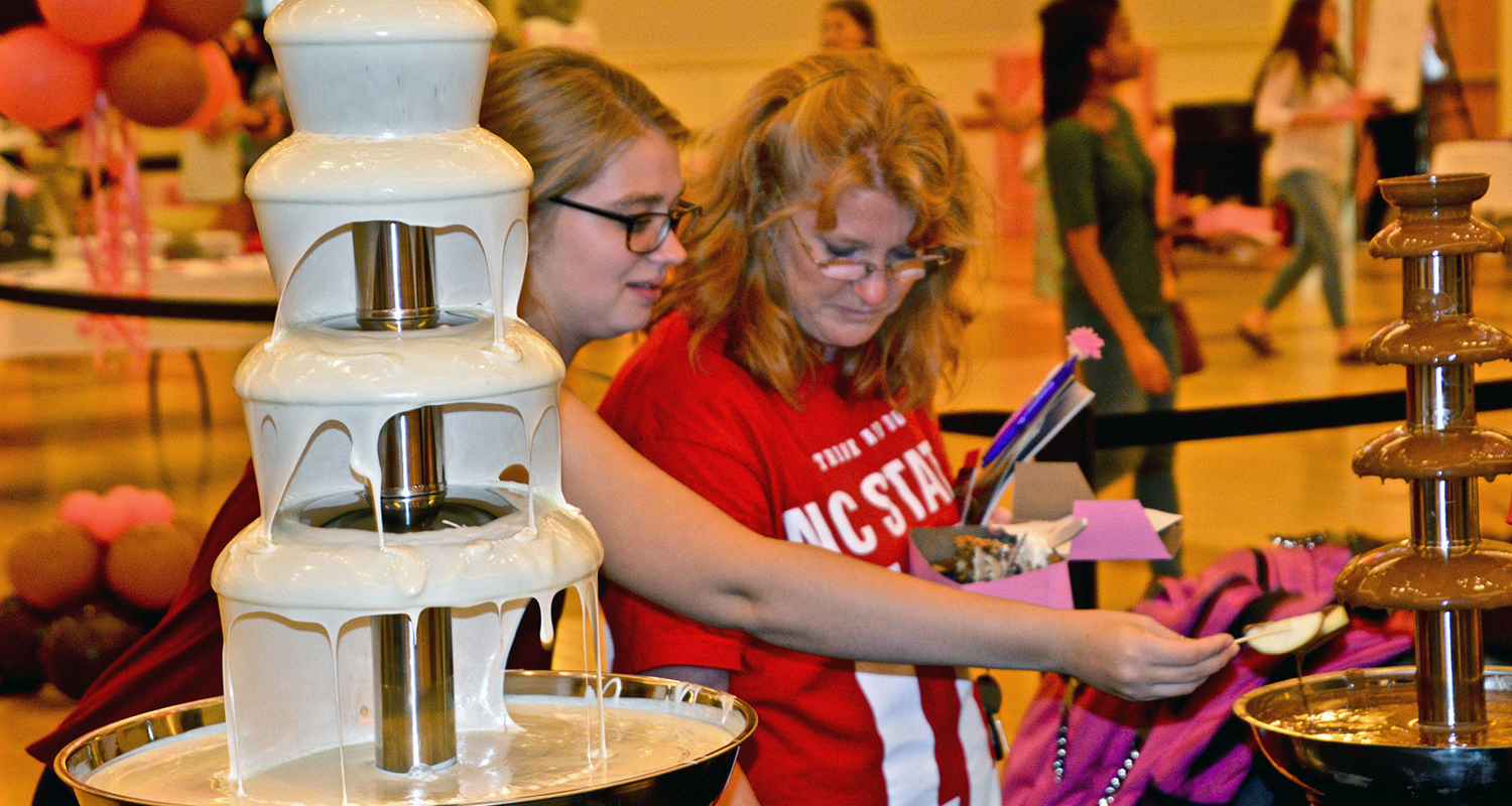 Two young women sample a treat at the NC State chocolate festival.