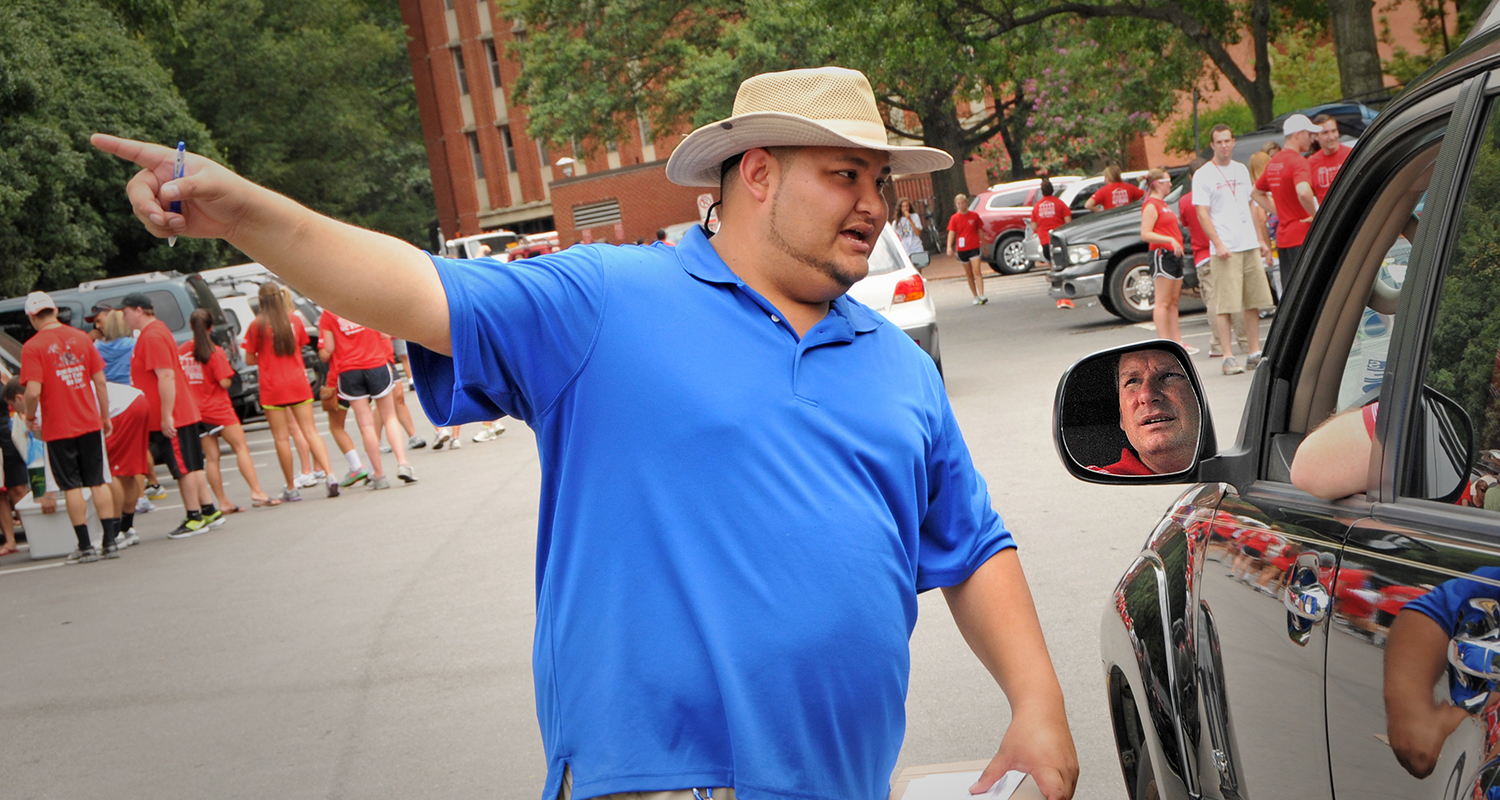 Transportation employee directs a dad on where to park after unloading during move-in.