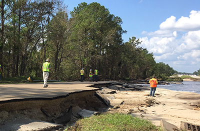 People stand on a washed-out road.