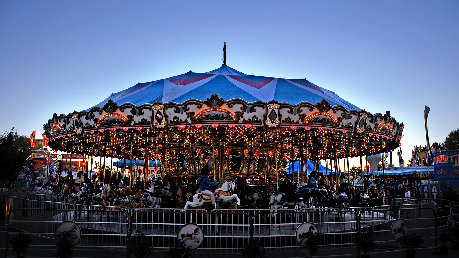At dusk, children ride a brightly-lit merry-go-round.