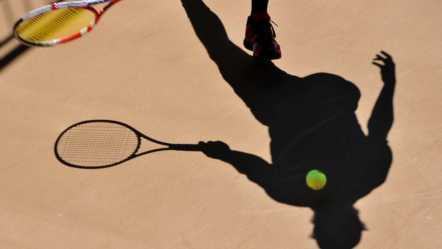 Photo of a tennis ball being struck by a tennis racket.