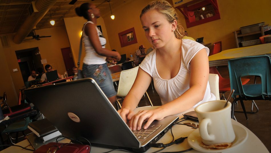 A young woman works on her laptop at a local coffee shop.