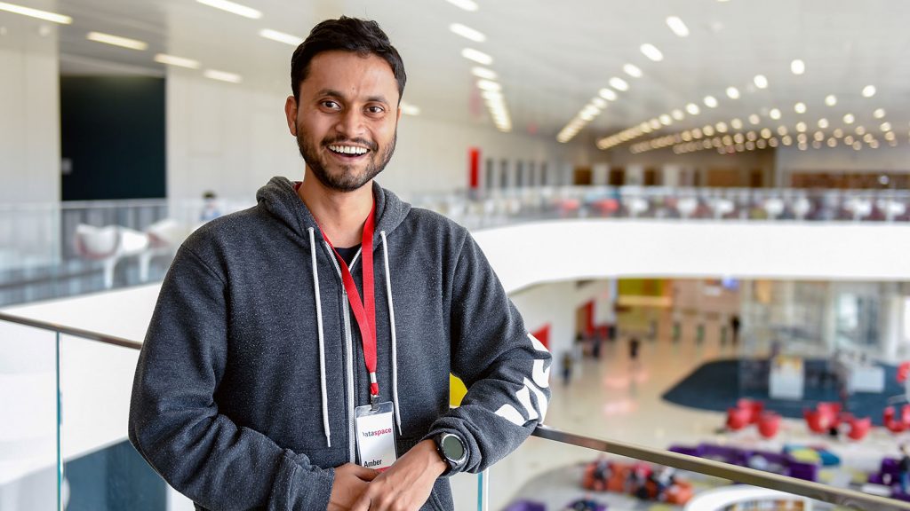 Male graduate student posing along balcony in Hunt Library