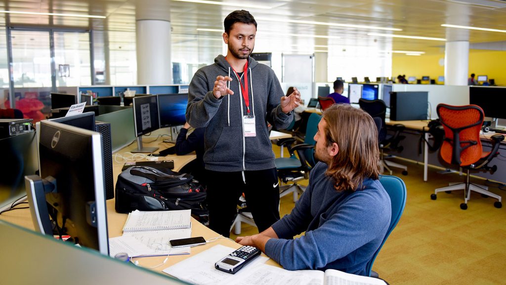 Two graduate students talking at a computer