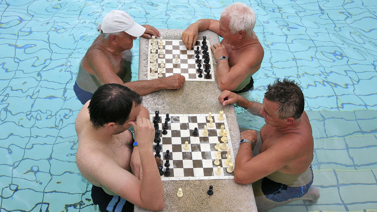 old men playing chess in a swimming pool