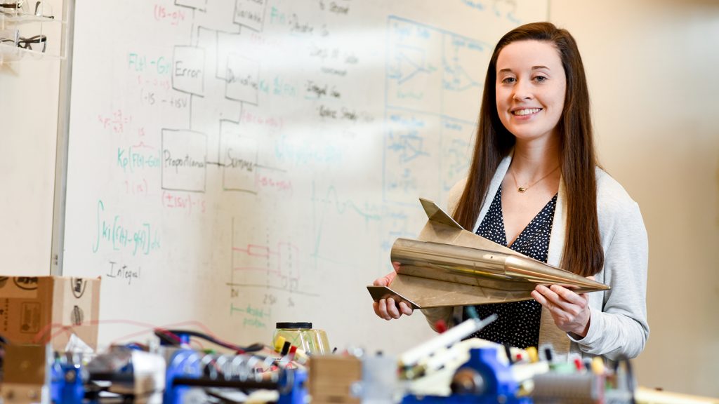 Madison Maloney holding a model of a jet in a lab.