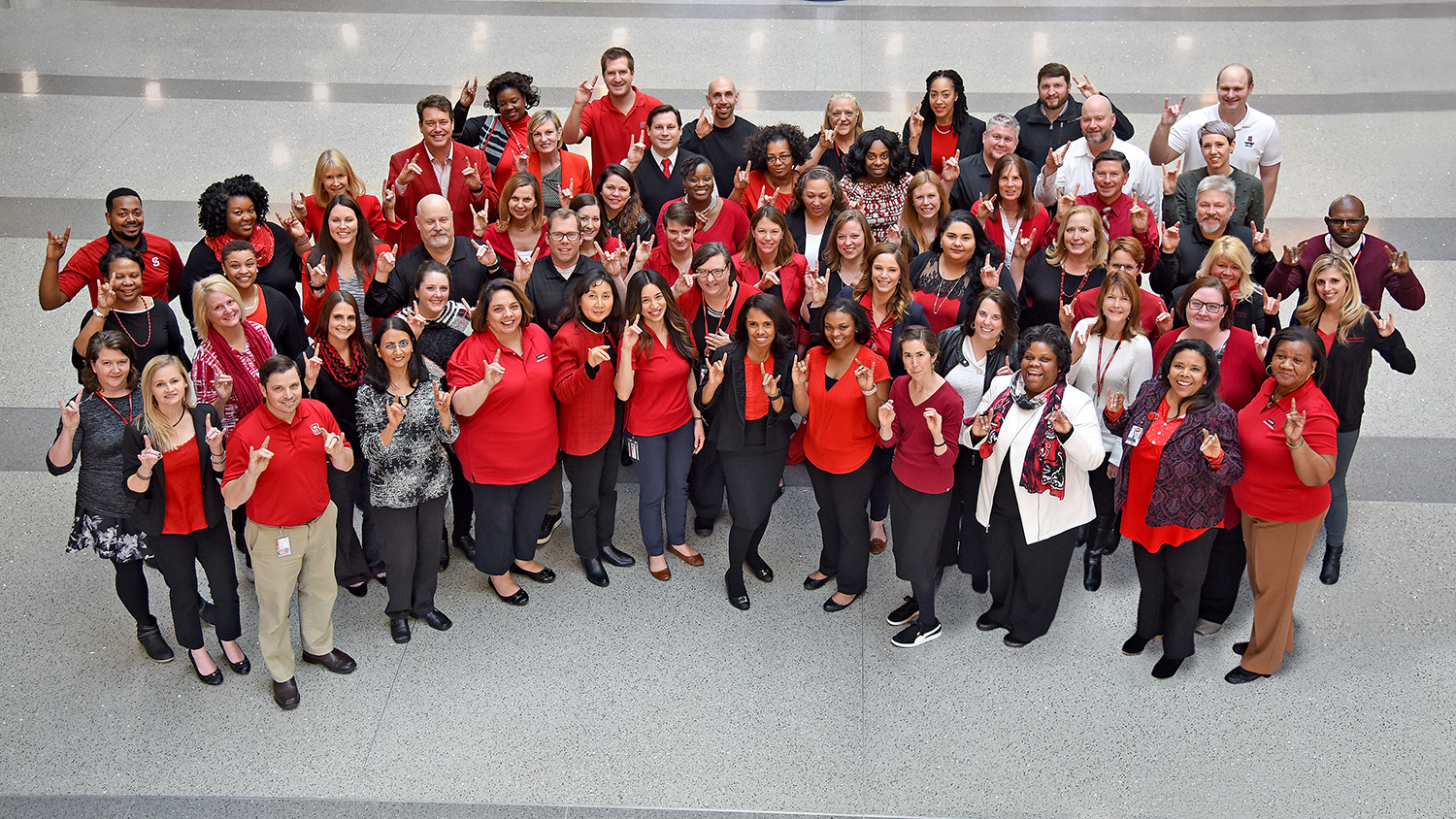 University Human Resources staff making the Wolfpack hand sign.