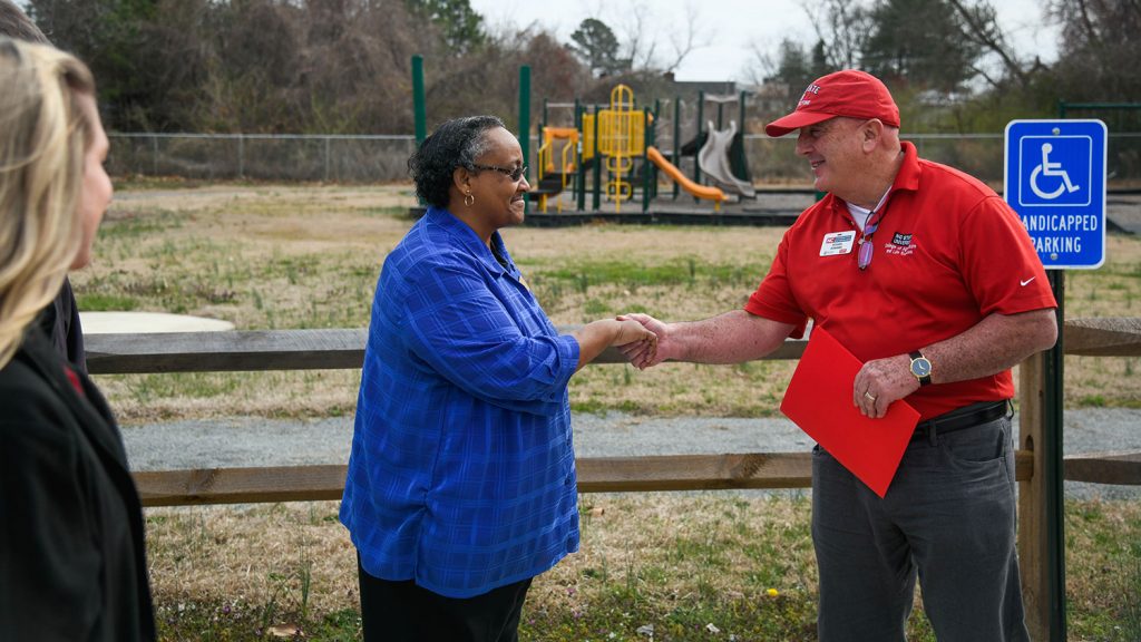 A man and woman shaking hands in front of a playground