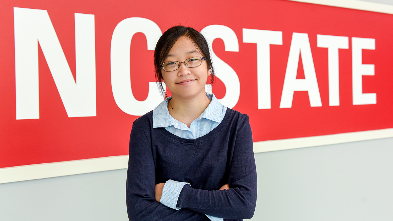 Sophomore Rachel Chen standing by an NC State sign.