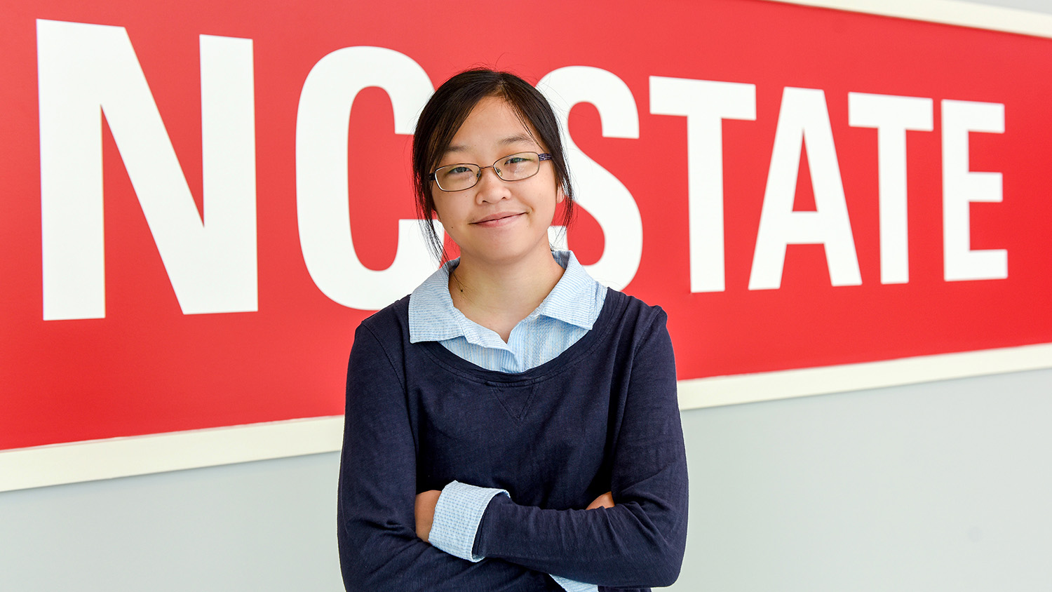 Sophomore Rachel Chen standing by an NC State sign.