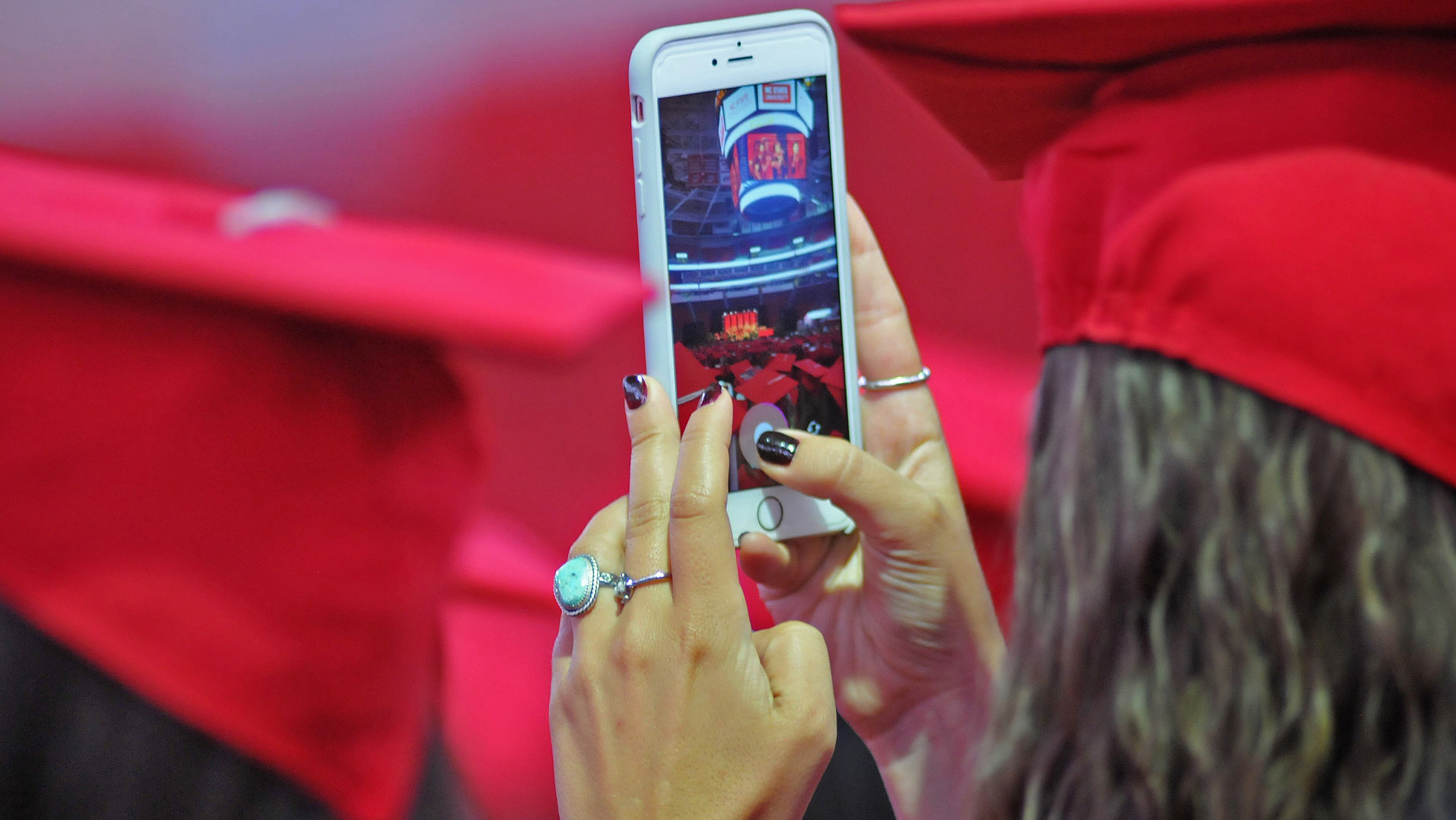 A graduating student takes a cell phone picture during commencement.