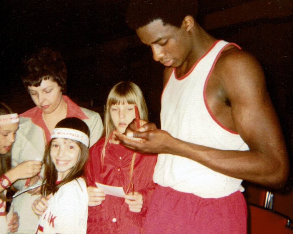 Basketball player signs autographs for kids.