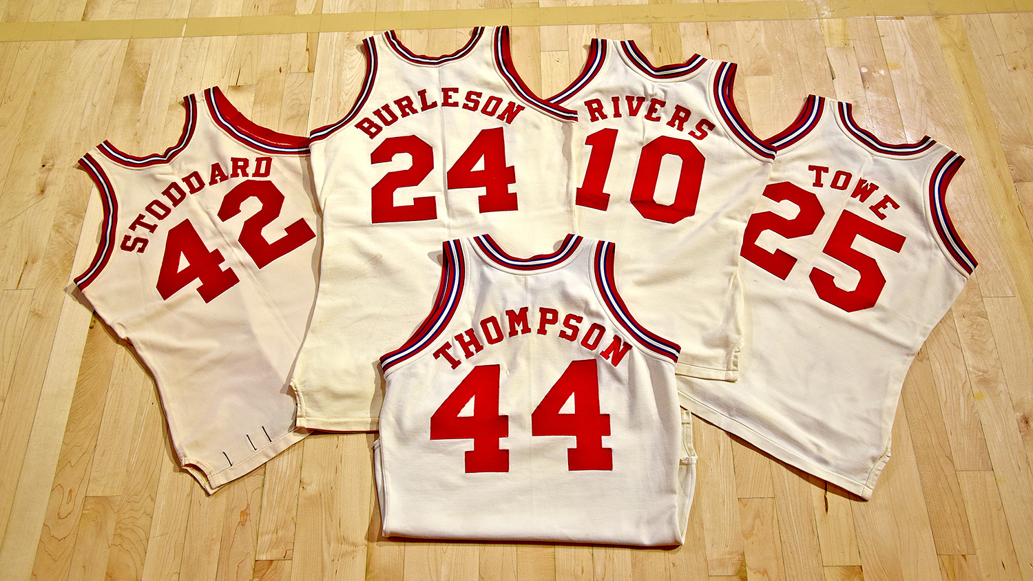 Five jerseys laid out on the floor of Reynolds Coliseum.