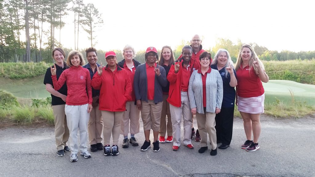 A group of NC State Staff Senate volunteers posing for a photo on a golf course