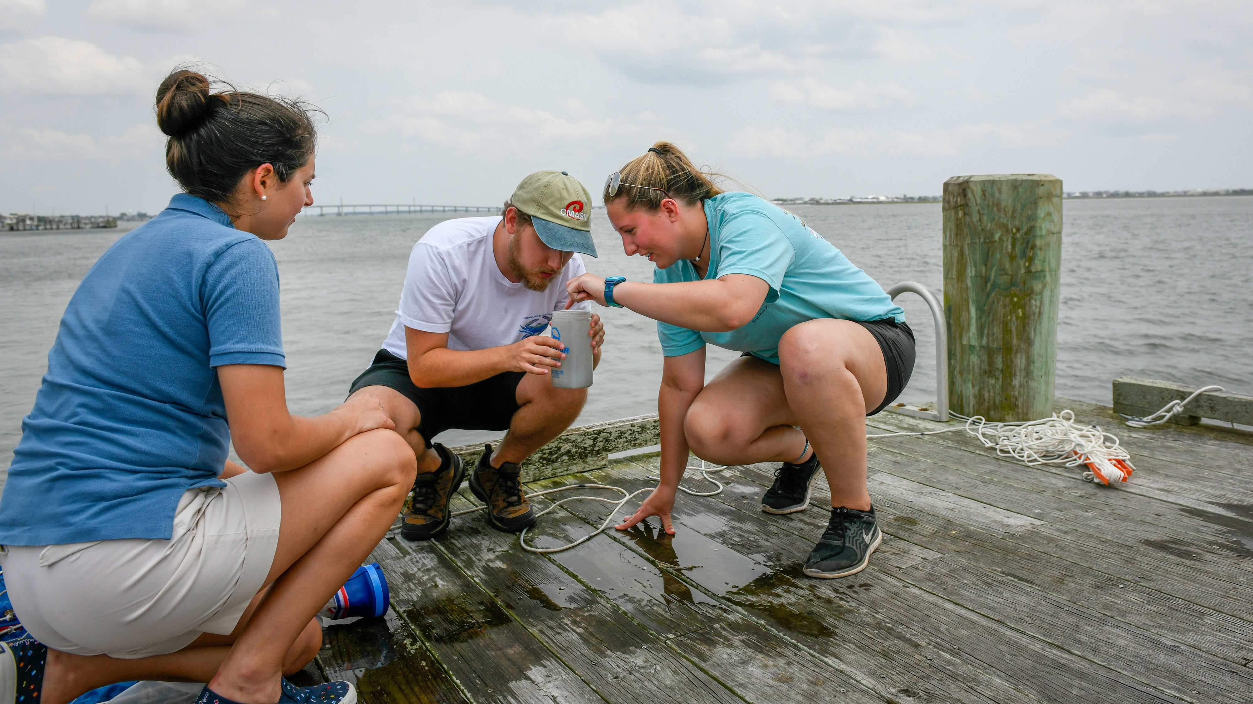 Two students and an instructor look at samples on the dock outside CMAST