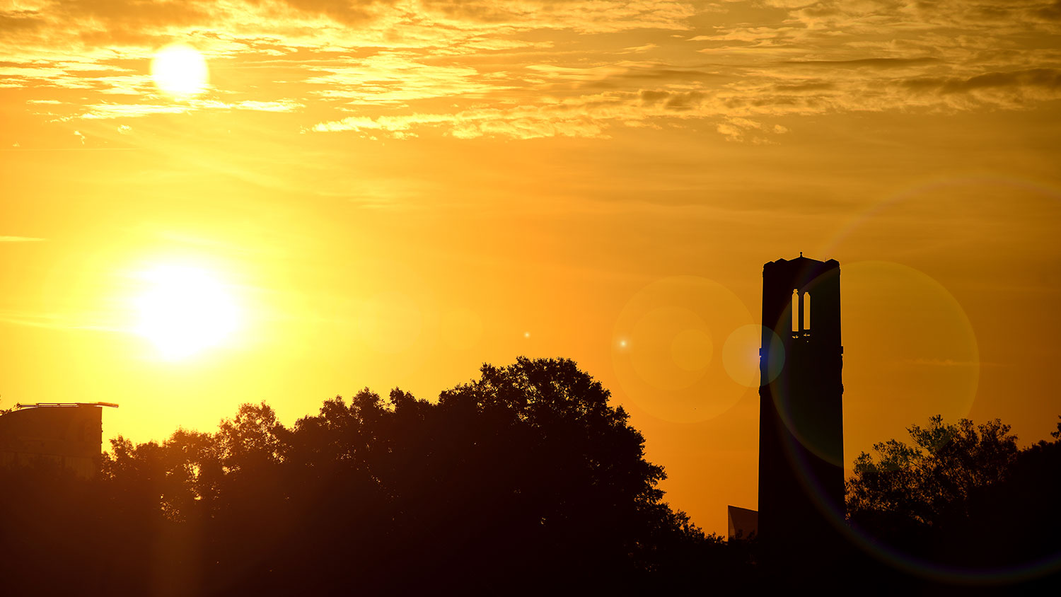 NC State's belltower with the rising sun