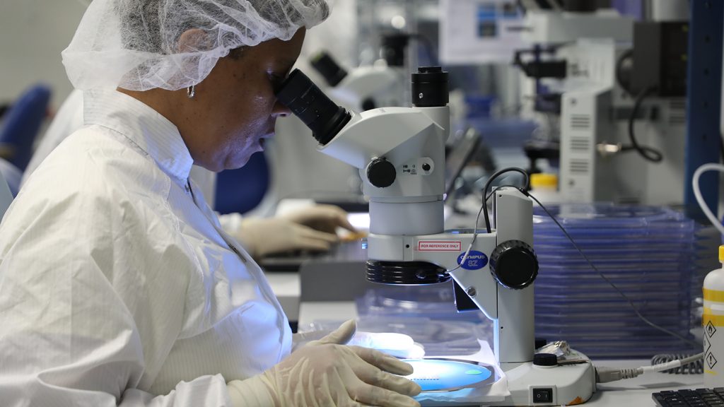 A woman examines a slide under a microscope in Phononic's headquarters.