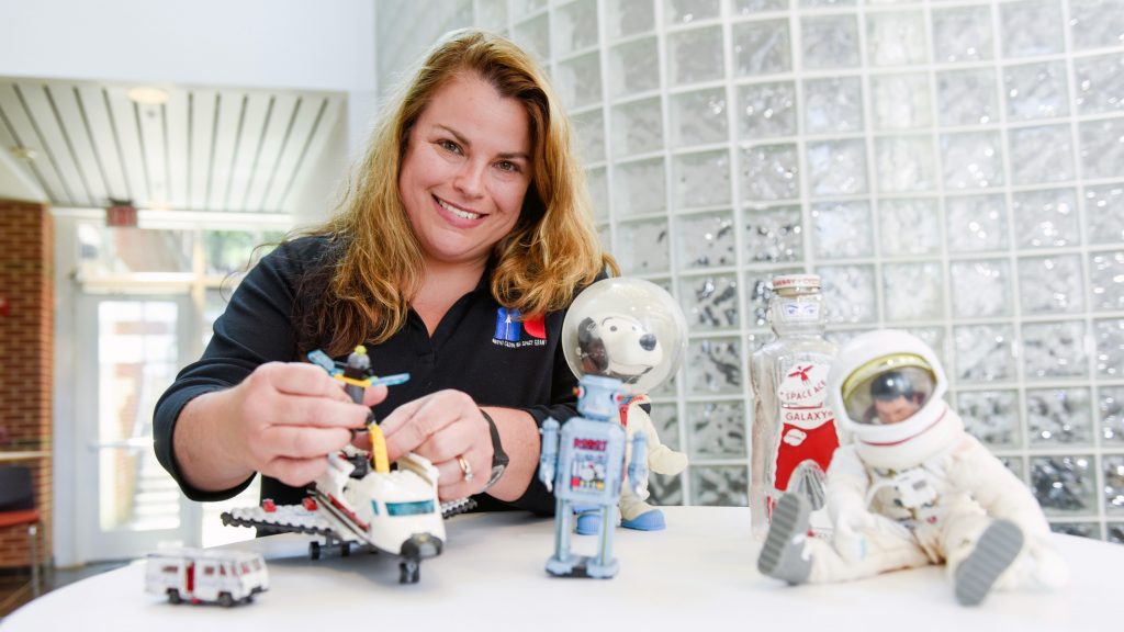 Jobi Cook, assistant director of North Carolina Space Grant, with space-related toys on a table.