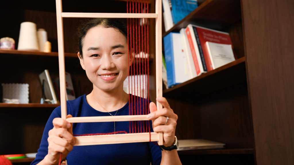 Xiaomeng Fang looks through a loom in her office.