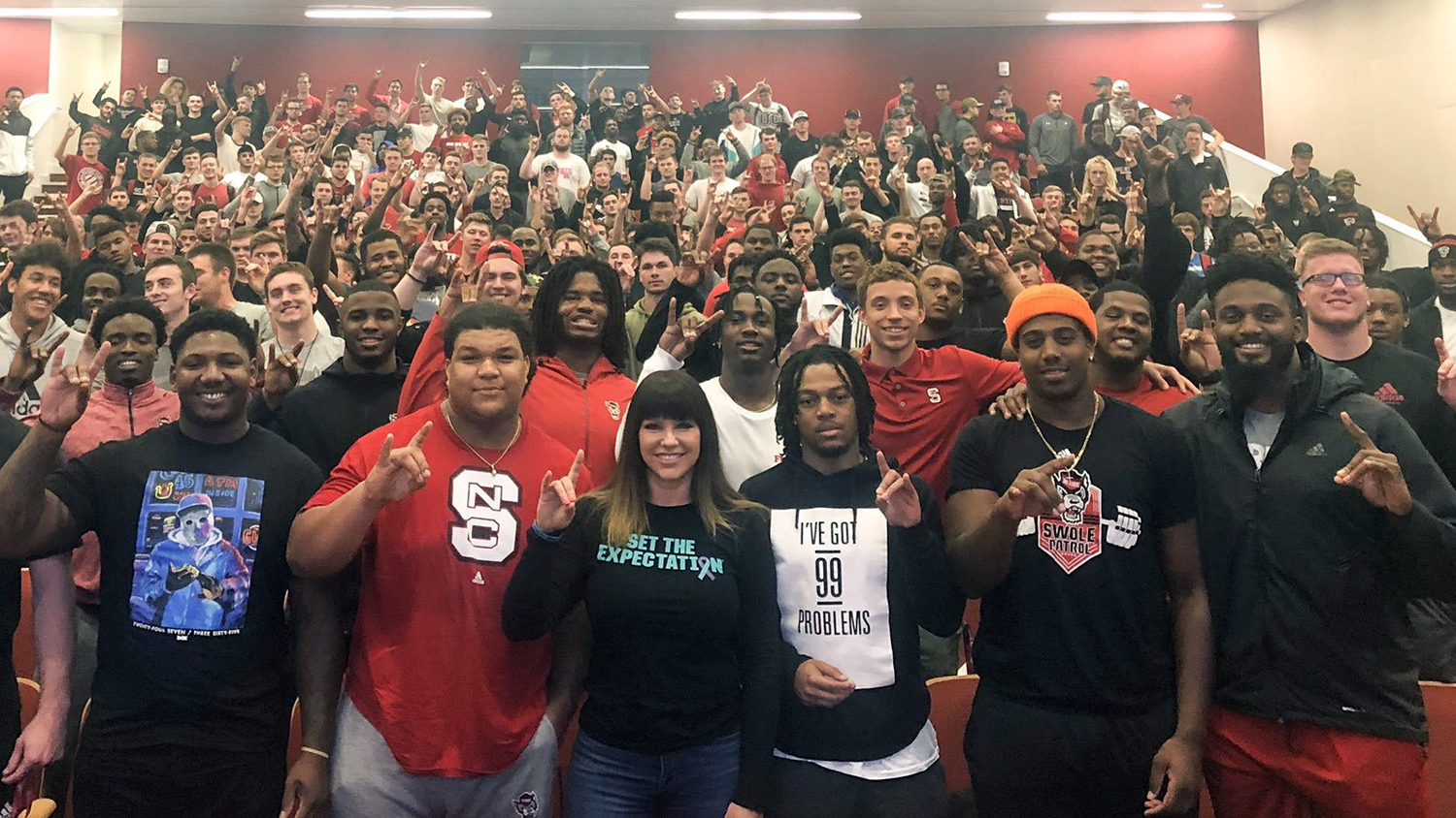 A group of student athletes pose with Brenda Tracy.