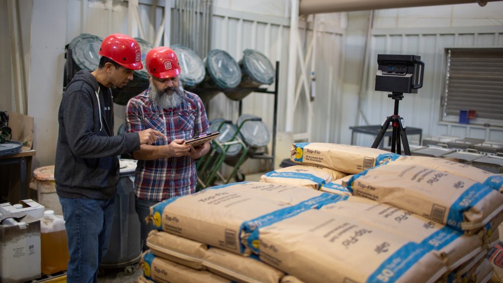 two men in hard hats working in a feed mill