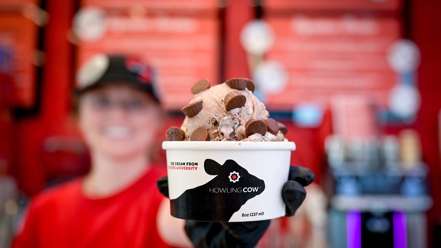 An employee at the Howling Cow creamery holds up a fresh scoop.