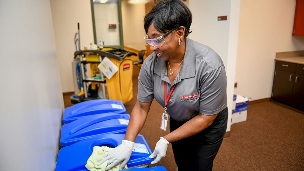 NC State housekeeping employee Benita Womack wiping a recycling bin