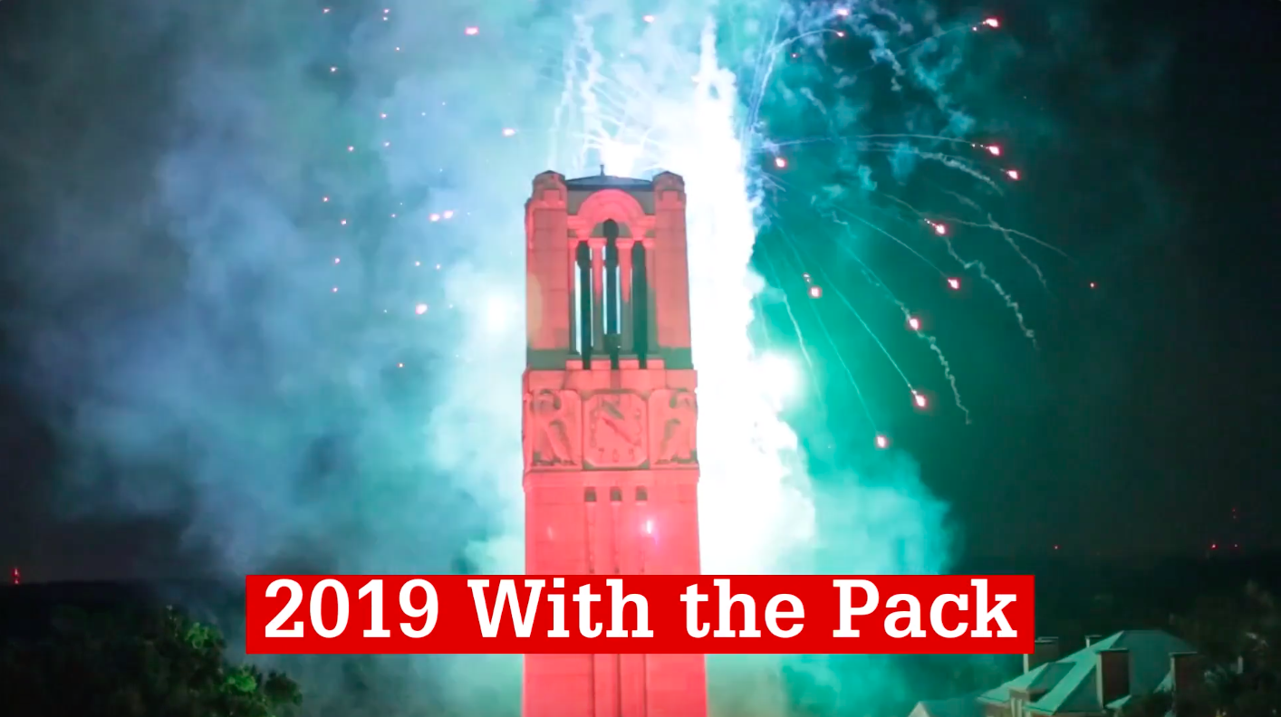 NC State's Memorial Belltower is lit red and surrounded by fireworks
