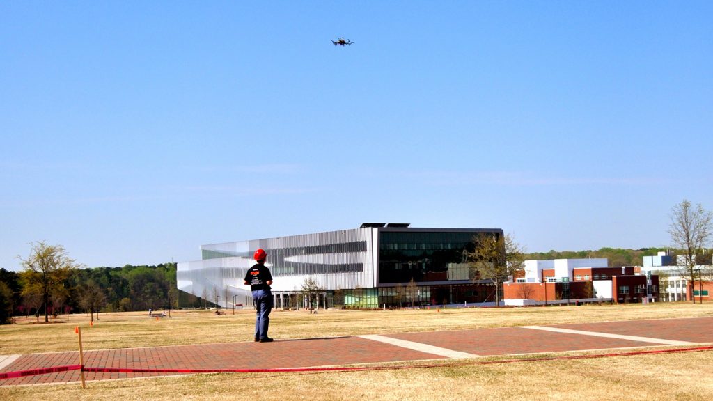 An individual flies a drone on NC State's campus